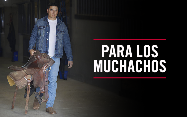 Para los muchachos. Un hombre vestido con un chaleco Justin y una silla de montar saliendo de un granero en la nieve.